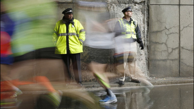 FILE - In this April 20, 2015 file photo, police officers stand watch as Boston Marathon participants race along the course in Boston. Multiple law enforcement agencies will provide security for the 120th Boston Marathon set to be run on Monday, April 18, 2016. (AP Photo/Robert F. Bukaty, File)